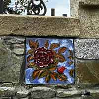 Kachel s růží zasazený do kamenného plotu